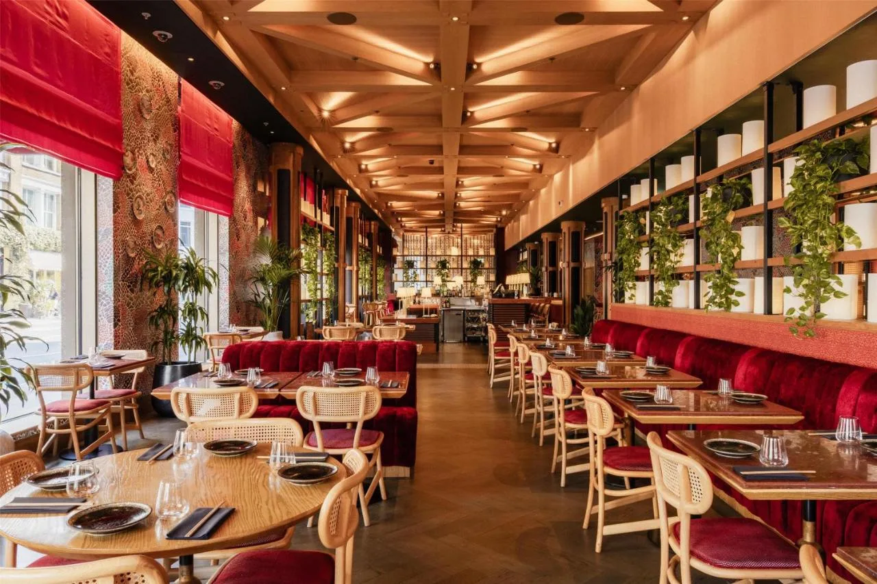 a restaurant with wooden tables and red chairs at Hart Shoreditch Hotel London, Curio Collection by Hilton in London